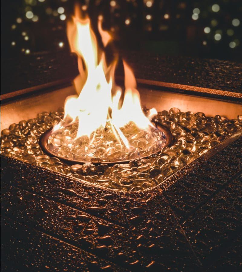 Flames in a big gas firepit with simple glass rocks surrounding the flames