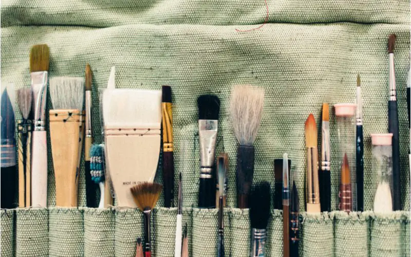 For a piece on what type of paint should you use to paint a picture frame, a number of brushes sitting in a canvas holder
