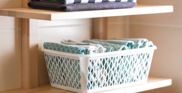 Featured image for a piece on bathroom towel storage ideas featuring floating shelves with a basket and towels sitting on the shelf
