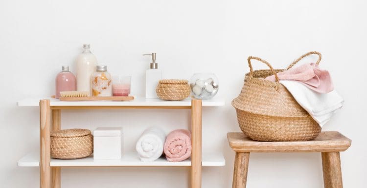 Bathroom shelf idea featured image featuring a natural unfinished wood shelf base with white shelves sitting against an extremely faint pink wall