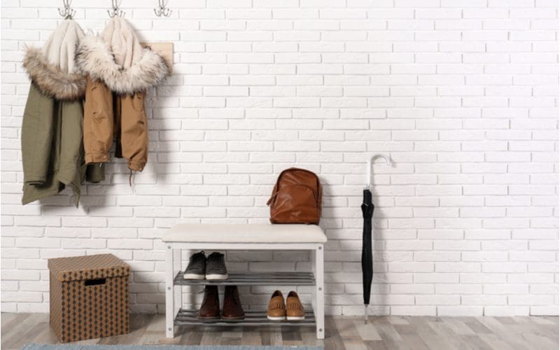 Two-Level Shoe Rack and Bench in front of a brick wall painted white in the entryway of a home