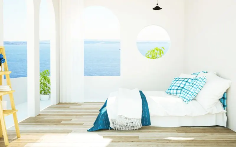 Mediterranean bedroom aesthetic idea with simple bright white walls and colorful blue accents with a round mirror to bring an airy feel into the room