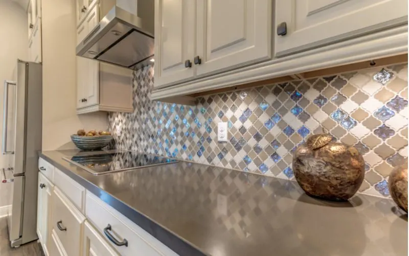 Farmhouse backsplash with multi-colored and tan and brown arabesque mosaic tile with cream cabinets