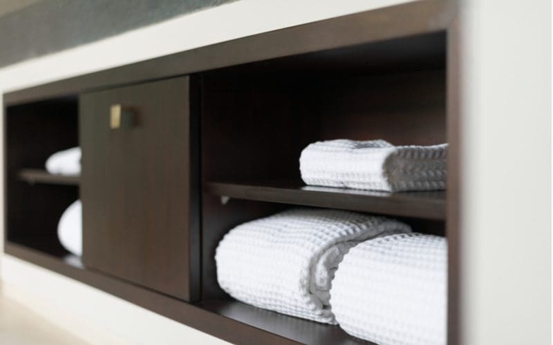 Bathroom towel storage idea featuring in-wall towel shelves in black color with metal pulls