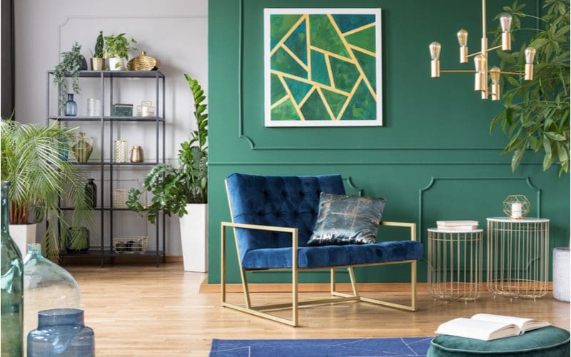 Photo of a blue couch living room idea with a green board and batten wall alongside a white accent wall with a dark grey metal shelving unit