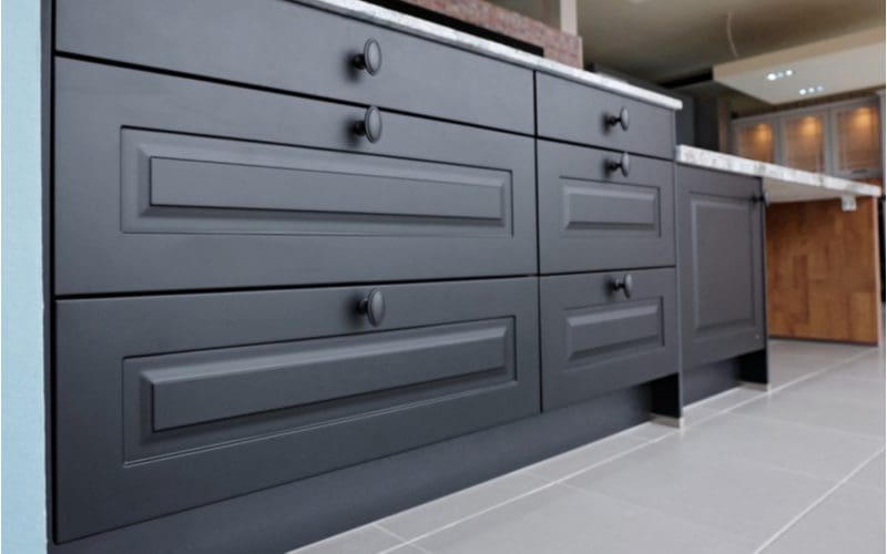 Black wooden kitchen cabinets with gray floors