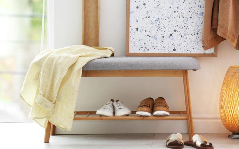 Modern open-front shoe storage idea for the entryway featuring a grey upholstered bench with an open bamboo-style shoe rack below