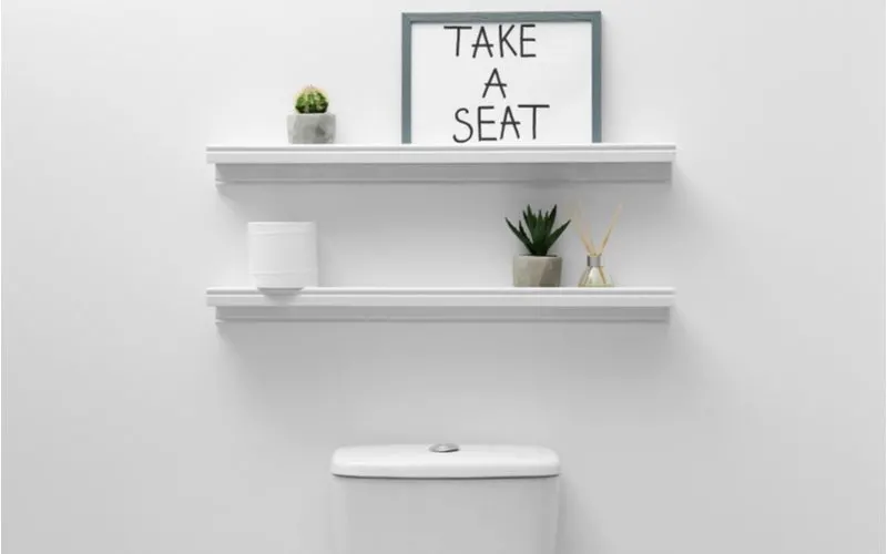 Floating bathroom shelf ideas in a white beveled design that's floating above the toilet