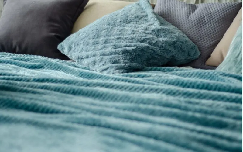 Teal bedding with sheets and blankets and a close-up shot of pillows for a piece on teal bedroom ideas