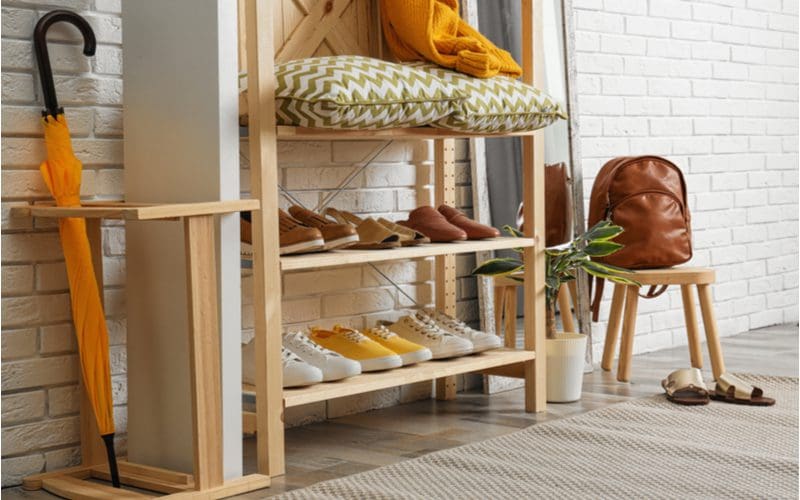 Farmhouse entryway shoe storage idea made of natural wood with an umbrella holder on the left