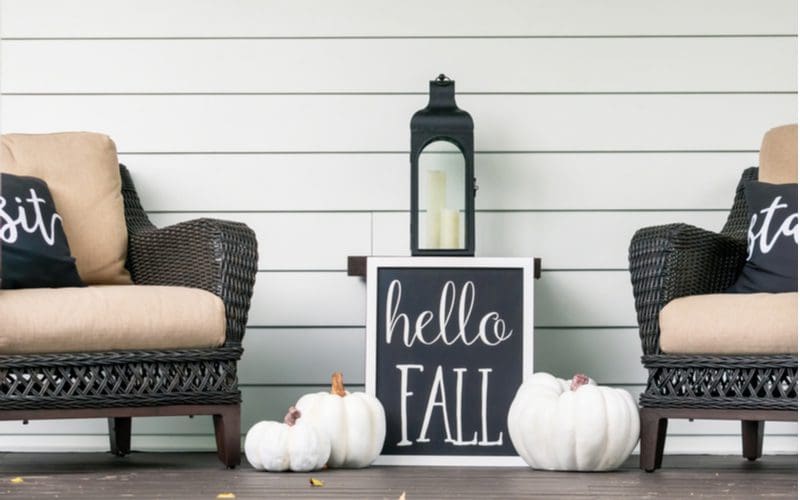 Farmhouse decor idea with a wooden sign that says hello fall sitting in front of a white shiplap wall