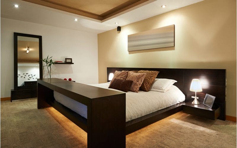Under the bed lighting in a photo as part of a mens bedroom idea that features a large and thick wood-framed bed