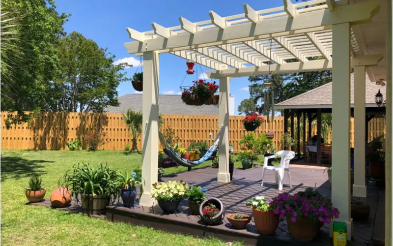 Idea for a traditional pergola in white color above a slightly-elevated composite deck