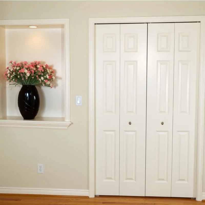 Bi-Fold White Closet Door ideas in a living room next to a built-in shelf on which a group of flowers in a vase sits