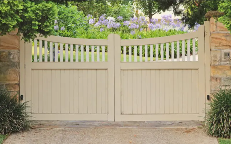 White wood driveway gate idea that mimics a picket fence