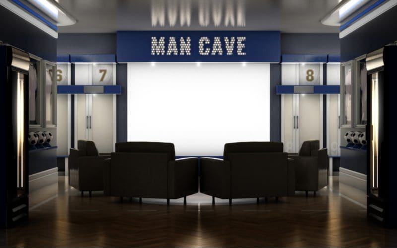 Sports locker room style man cave idea featuring a dark blue lined room with white accents and a stamped backlit metal sign that says man cave