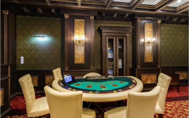 Man cave idea with a poker table in the middle of an ornate wood-paneled room in the basement of a home