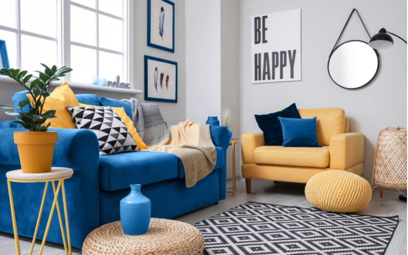 Blue couch in living room idea with yellow pots and chairs and ottomans as an accent piece