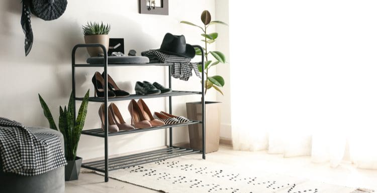 Entryway shoe storage idea featuring a four level metal rack in black color next to a white wall below some purse hooks