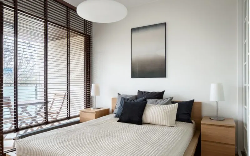 Black slatted window blinds on the left side of a bed for a piece on mens bedroom ideas