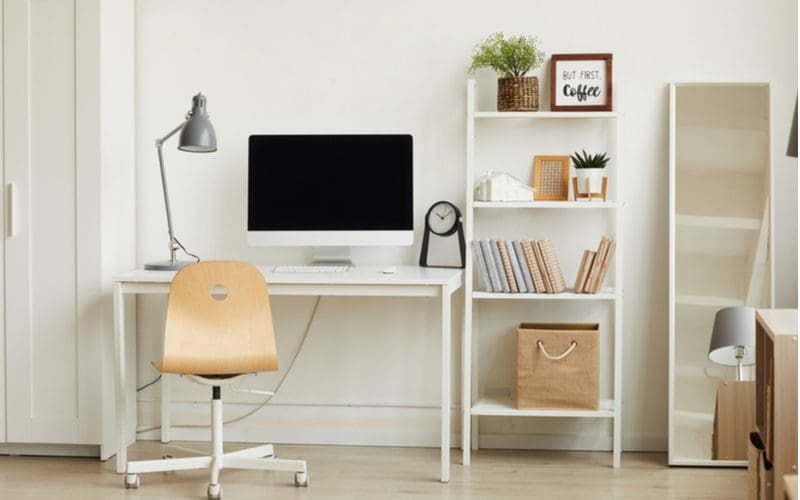 Plain white dorm room idea with white bookshelves, desk, and a simple natural wood office chair
