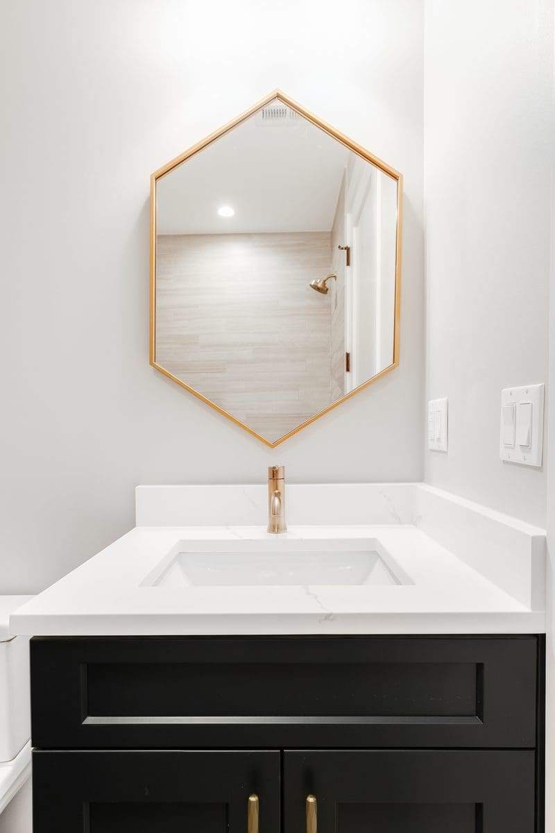 Light and dark white and gold bathroom idea with white walls and a dark vanity with a white top