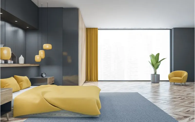 To help illustrate what color curtains go with gray walls, dark gray walls with orange curtains and orange accents pictured in a modern studio bedroom and living room apartment