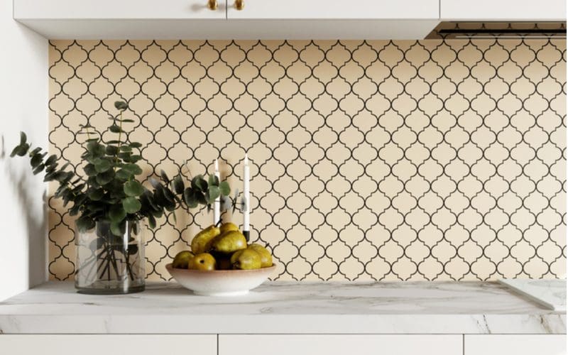 Beige colored arabic-style farmhouse backsplash idea with pears and a simple plant on the counter