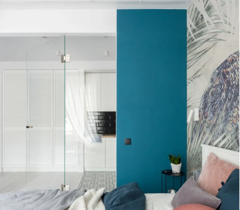 Modern teal accent wall with a mural on the right wall and a glass door to the left