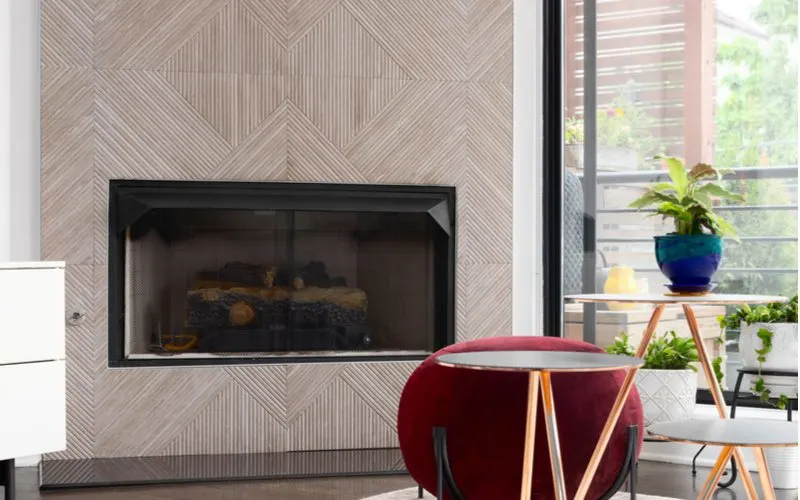 A fireplace tile idea with grey tile with lots of vertical and diagonal lines running down each tile forming a triangle pattern