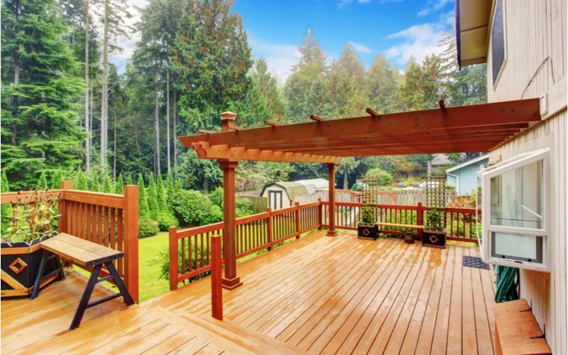 Wooden deck with an attached pergola bolted to the side of the house with multiple layers on the deck