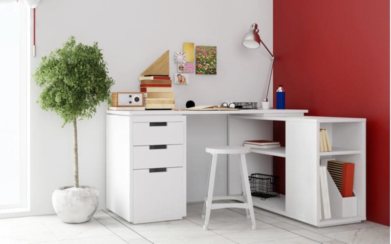 To symbolize the standard desk sizes, a white corner desk in a red and white room