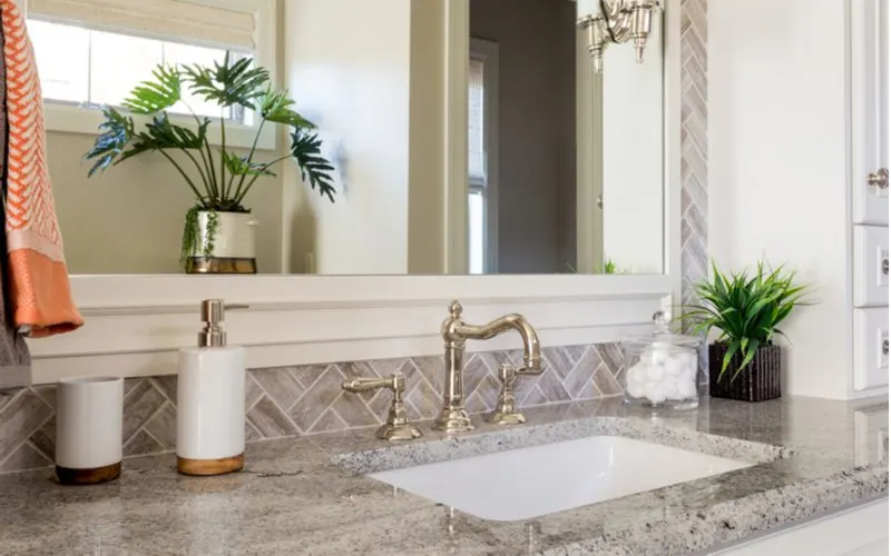 White and gold bathroom countertop decorations sitting on a grey quartz vanity top