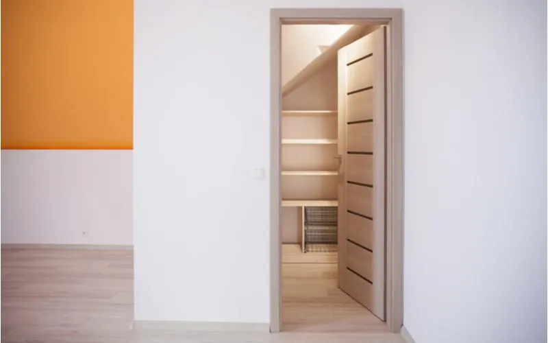 Unique slotted closet door idea in a white and orange painted room