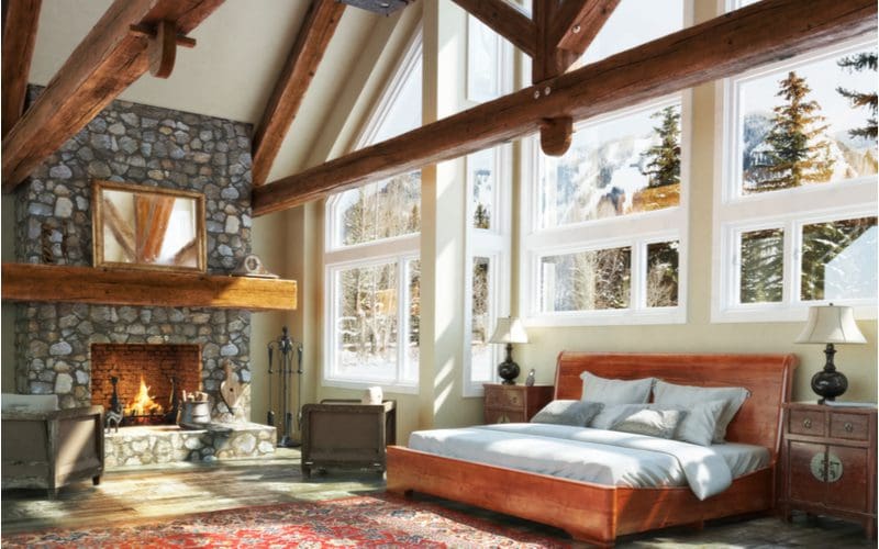 Giant bedroom with a couch next to the fireplace with big picture windows above the bed