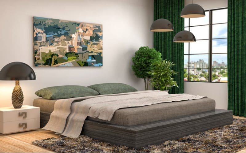 Idea for a grey bedroom with a grey bed and linen with grey accents throughout and dark green curtains on either side of the window