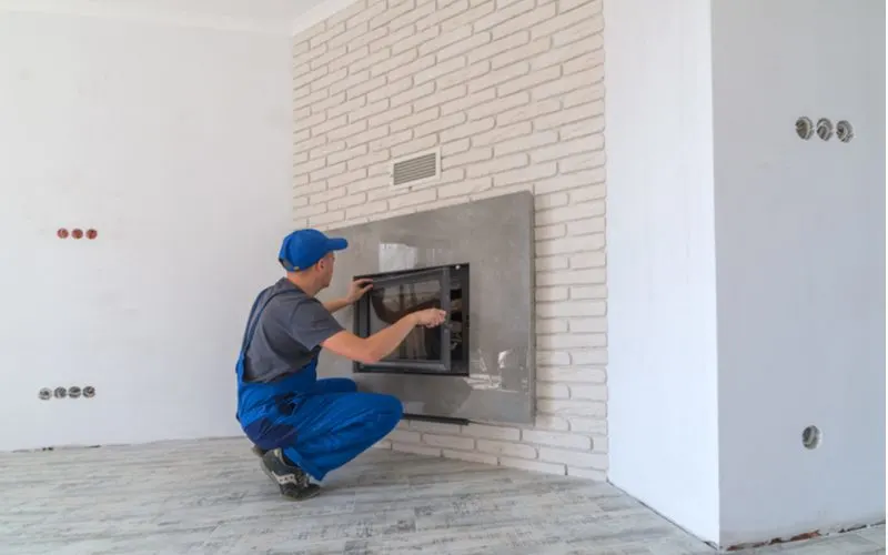Guy installing a gas fireplace in a fake brick wall