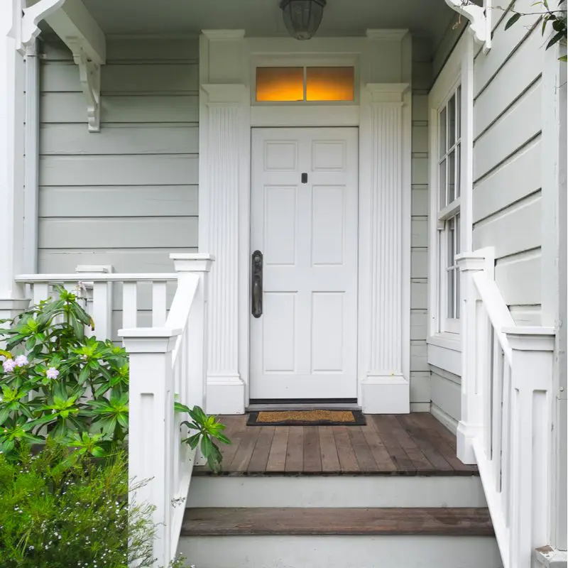 White front door on a gray house as viewed from the front walkway