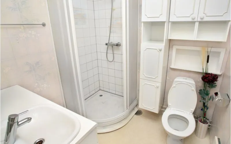 Idea for a small bathroom with a shower with a small modular corner shower next to a toilet below a bunch of storage wall cabinets