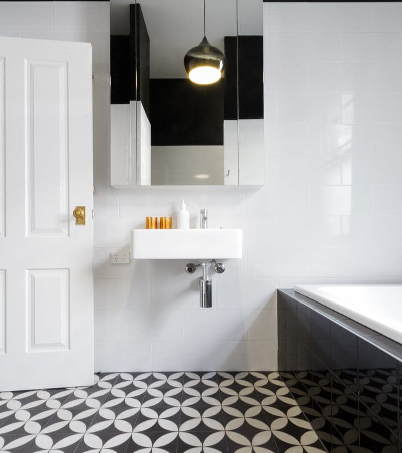 White, gold and black bathroom idea with white walls and black and white patterned floor tiles