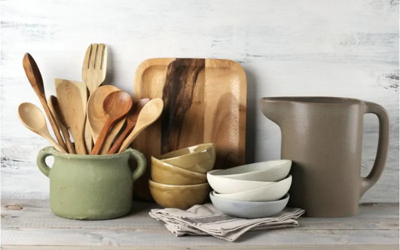 Natural wooden kitchen utensils and stone cookware sitting on a barnwood counter