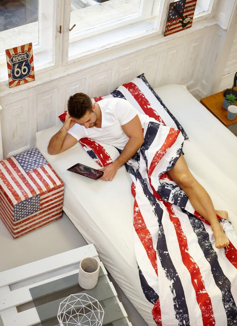 Americana-themed bedroom aesthetic idea with Colonial-style wainscoting and American flag end tables, wall decorations, and bedspreads