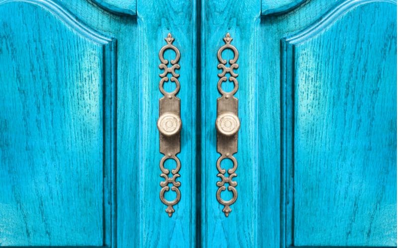 Blue Door With Brass Door Handles pictured in an up-close image for a roundup on closet door ideas
