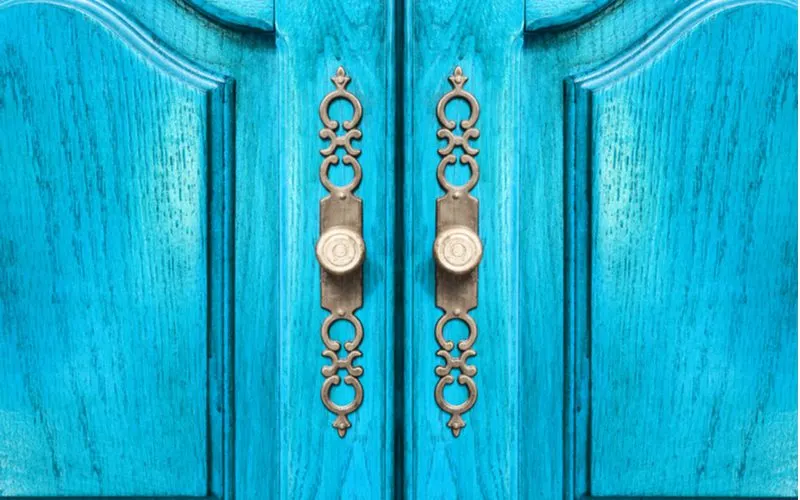 Blue Door With Brass Door Handles pictured in an up-close image for a roundup on closet door ideas