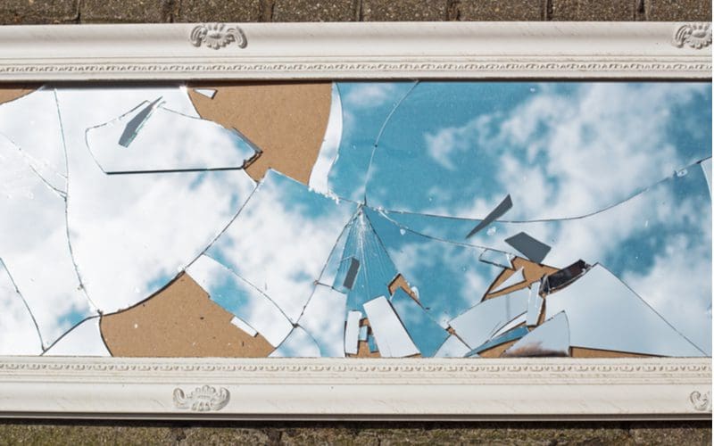 Image for a post on how to fix a broken mirror that shows a framed mirror broken in many spots in the middle after being dropped