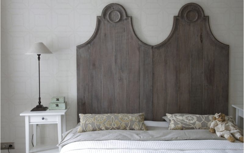 Grey headboard in front of a white wallpapered wall with grey sheets as inspiration for a grey bedroom idea