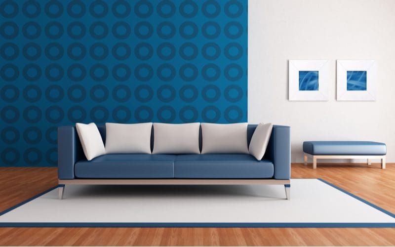 Mid-century modern living room with a blue wallpapered wall with round circles, a blue upholstered couch and bench with white accents, and a white rug with blue trim