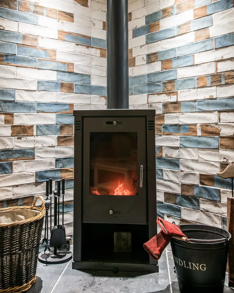 Modern wood burning stove against a blue, white and brown tile wall