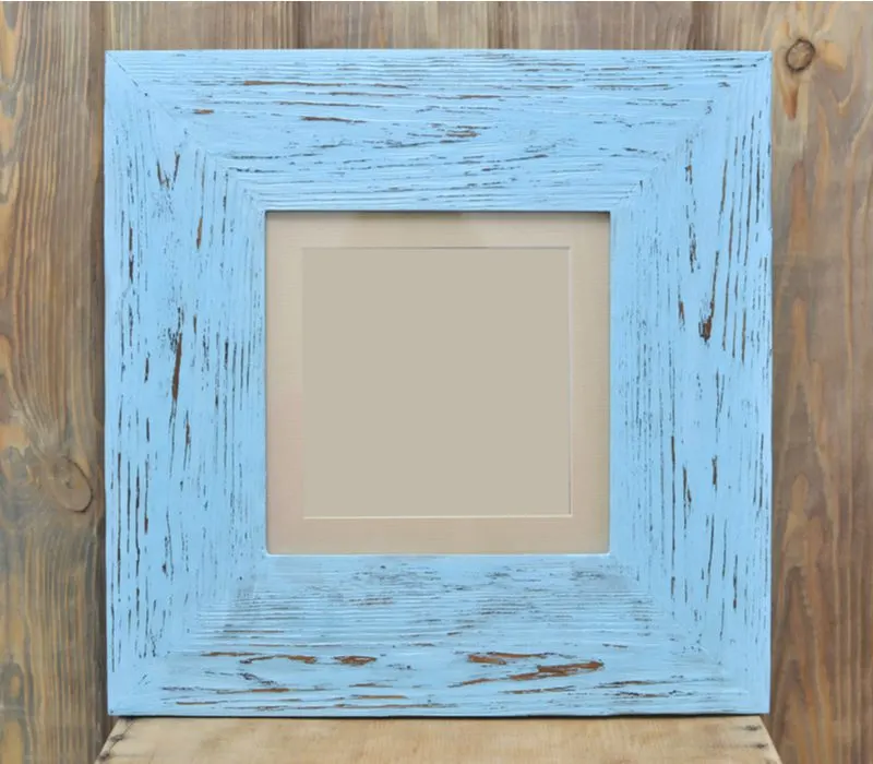 Wooden painted picture frame sitting on a barn wood shelf