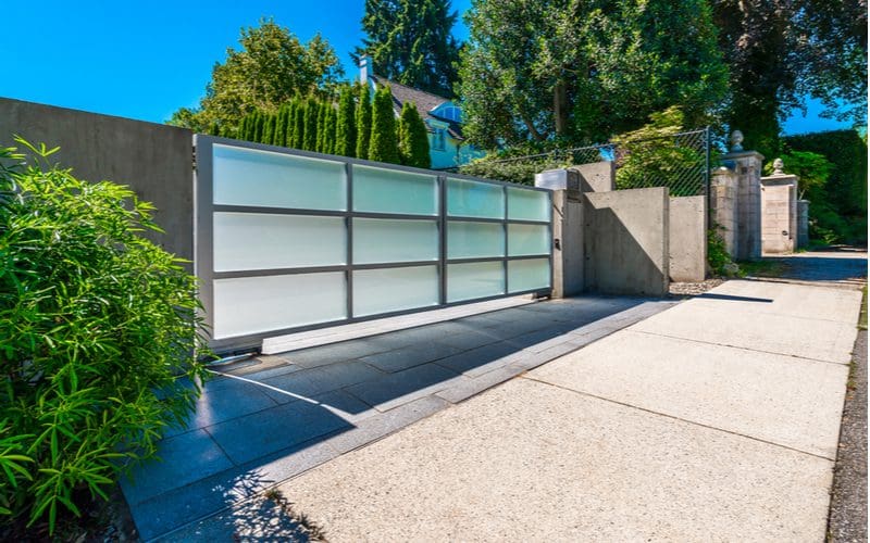 Frosted glass driveway gate idea between a concrete property fence